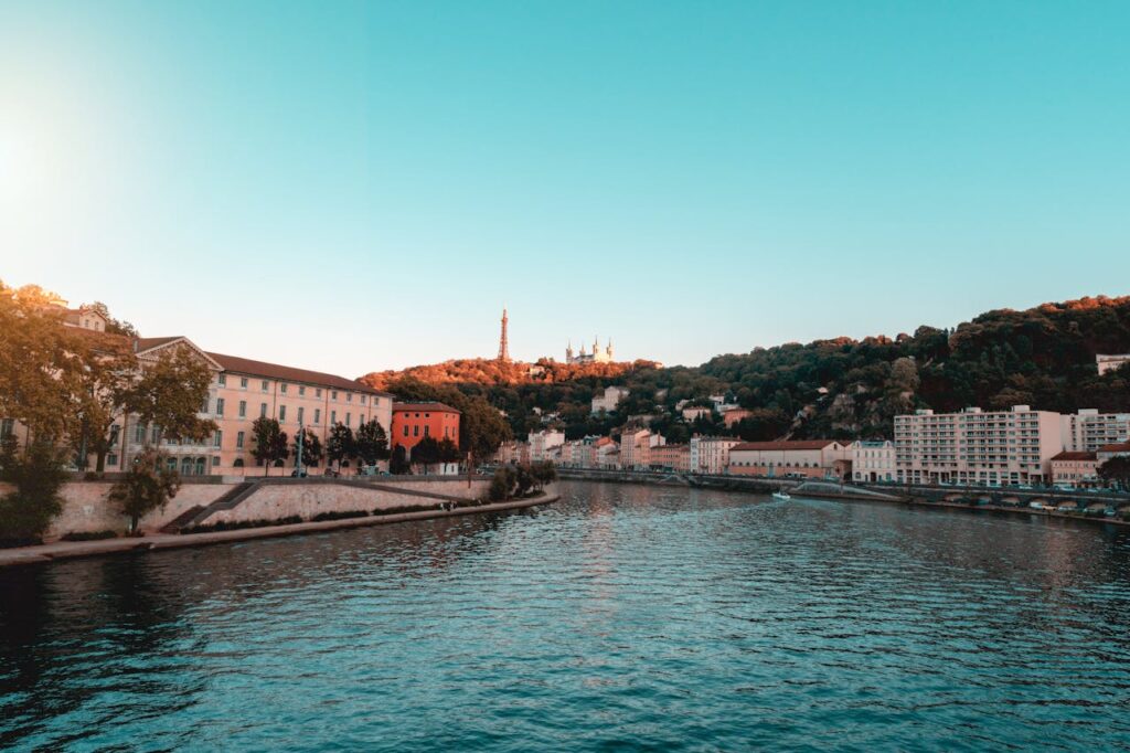 Lyon cityscape with river, buildings, and famous landmarks at sunset.